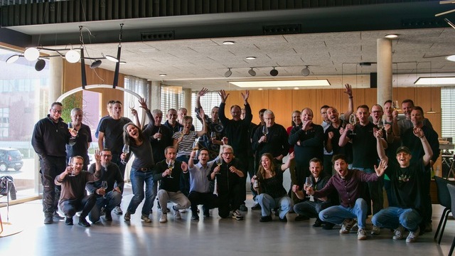 SATTLER Lighting Team 2025. SATTLER staff from production and the office standing together as a group in the showroom, glasses in hand and smiling. | © SATTLER