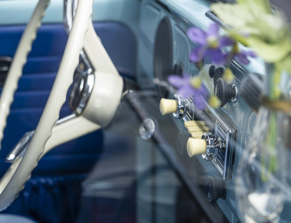 Innenansicht eines Oldtimers mit weißem Lenkrad und blauer Innenverkleidung, ebenso eine kleine Vase mit lila Blumen oberhalb des Radios. | © Andreas Körner | bildhübsche Fotografie