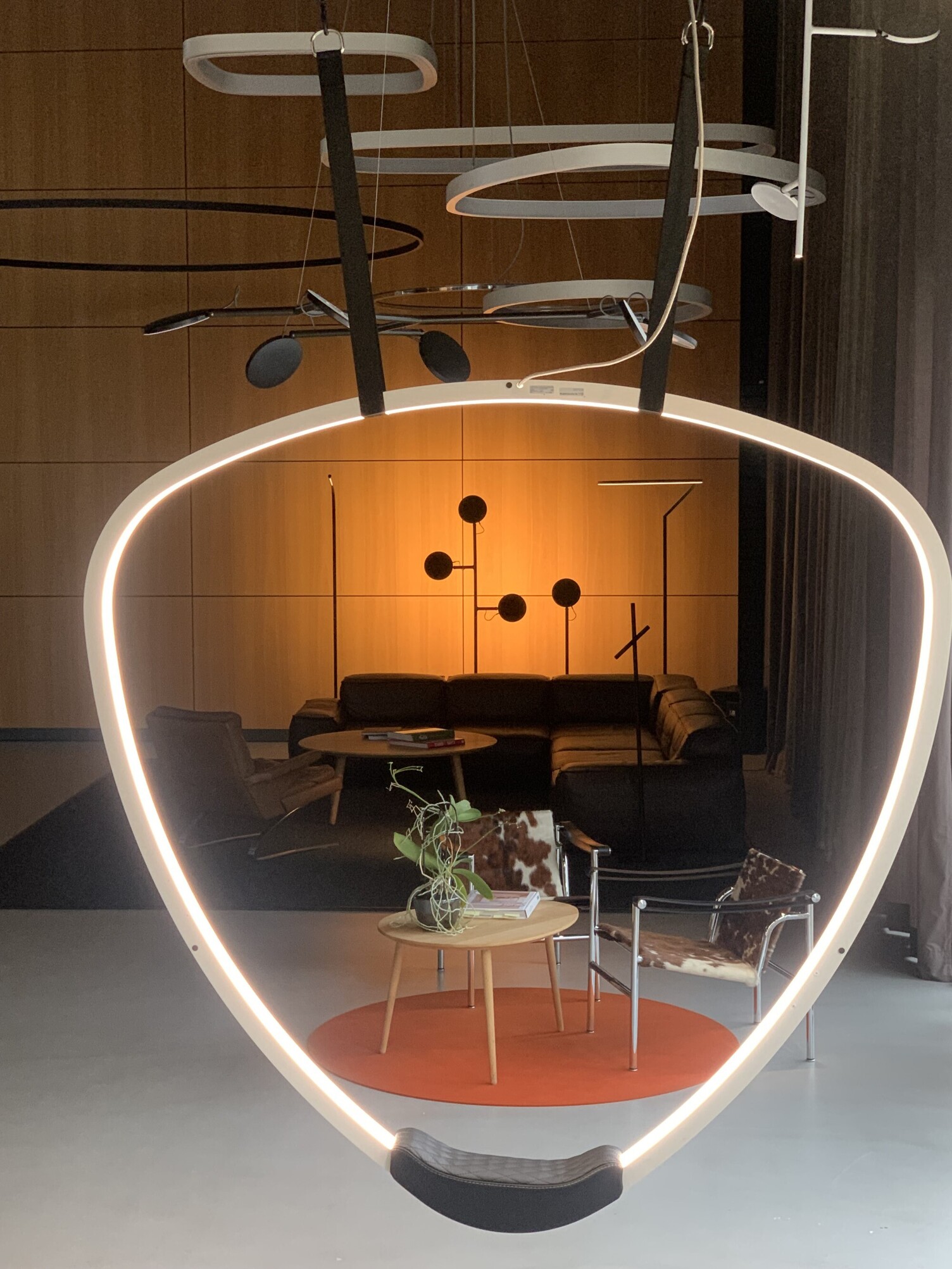 Leuchten-Showroom Sattler, Blick durch die dreieckige SOFT-DELTA-Lichtschaukel auf die Stehleuchten: AVVENI Floor, PALITO Floor, Fino Floor und Insospeso Floor.