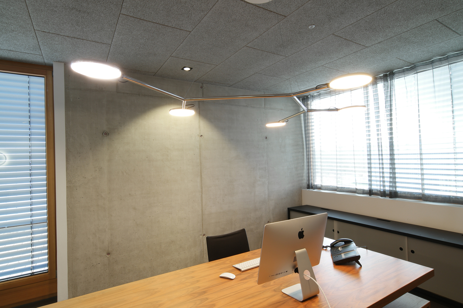 Branched luminaire made of polished aluminium with 5 movable flat, round luminaire heads, AVVENI Pendant 5 Type 3, suspended above a modern office desk.