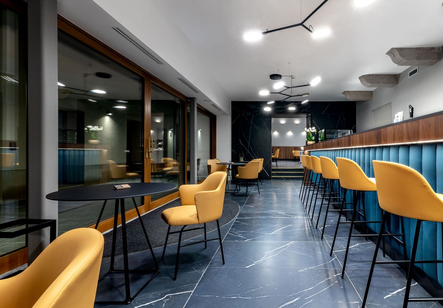 Blaue Restaurantbar mit gelben Hockern und abgependelten schwarzen verzweigten Leuchten mit 6 flachen runden Leuchtenköpfen - AVVENI Pendant 6.