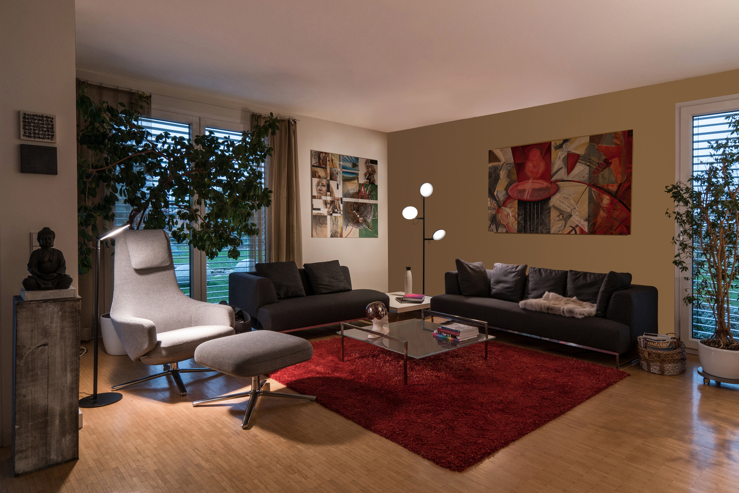 Wohnzimmerlandschaft mit verschiedenen Dekorativen Elementen und einer Stehleuchte mit einem Kopf neben Sessel und einer Stehleuchte mit drei Köpfen zwischen zwei grauen Sofas.