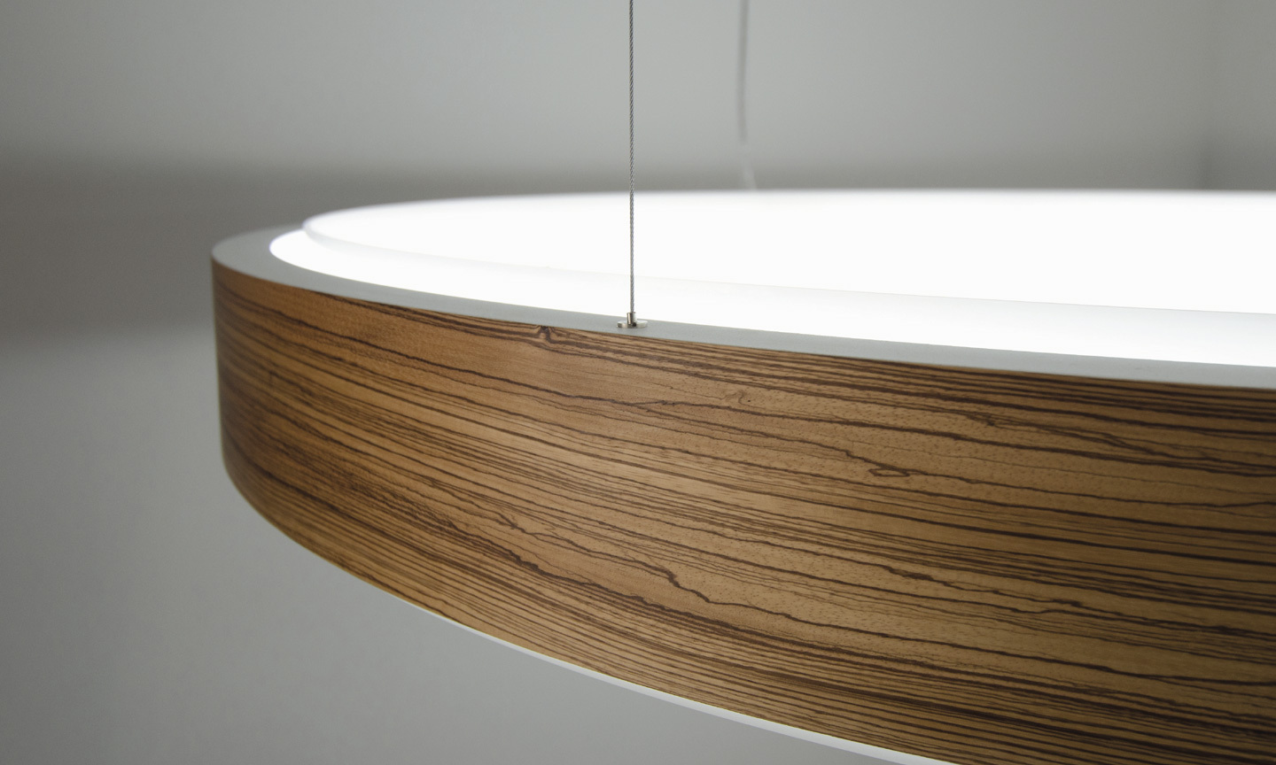 Ausschnitt einer großen Ringleuchte CIRCOLO mit elegant gemasertem Holzfurnier auf Außenradius.
