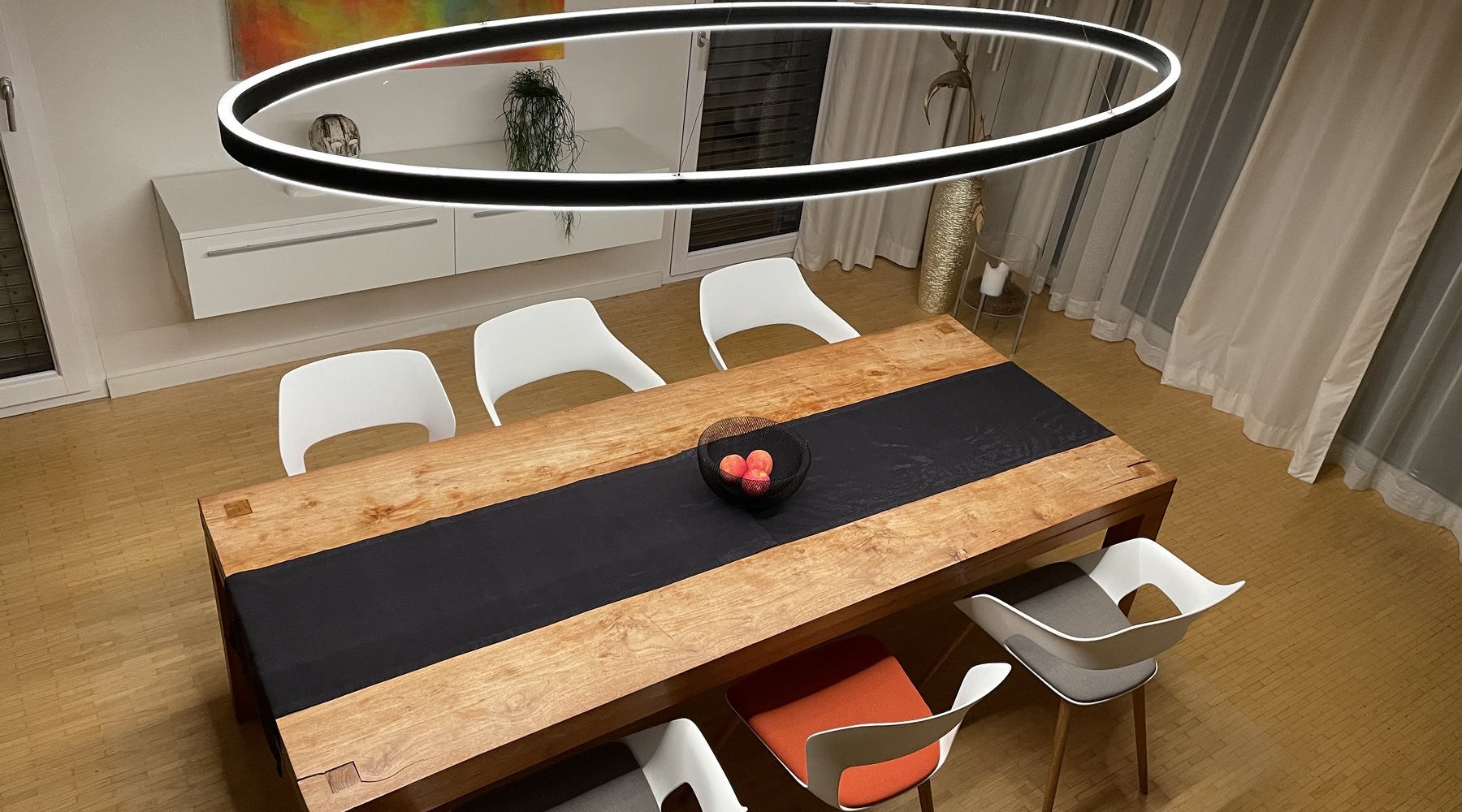 Elliptische Ringleuchte DOPPIO ELLIPSE über rechteckigem Esstisch Elliptische Ringleuchte Doppio Ellipse direkt und indirekt leuchtend über modernen Esszimmer-Holztisch.