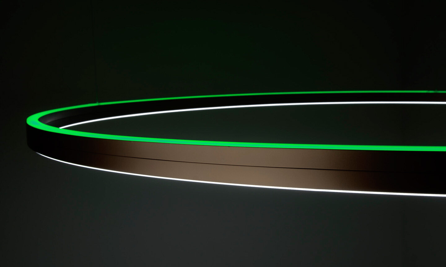 Ausschnitt der Aluminium-Ringleuchte Doppio direkt/indirekt mit RGB-Licht (grün) auf indirekter Seite.