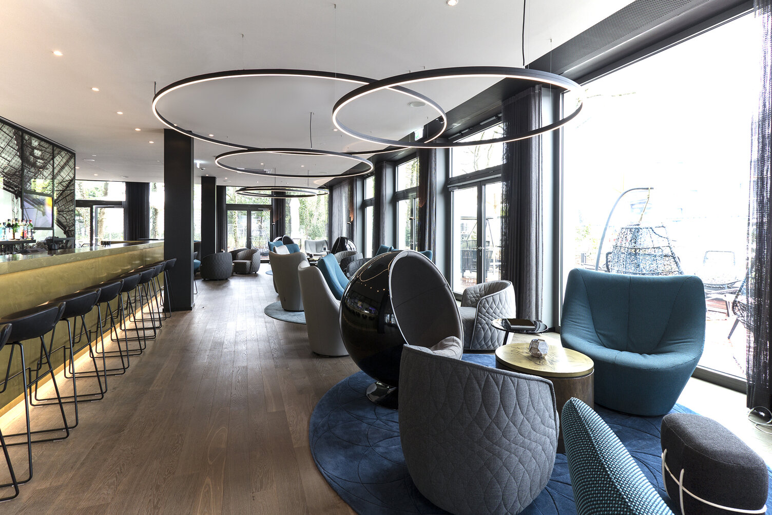 Schwarze Ringleuchten DOPPIO über blauen Sesseln der Motel One Hotel Bar Schwarze Ringleuchten DOPPIO über blauen Sesseln der Motel One Hotel Bar