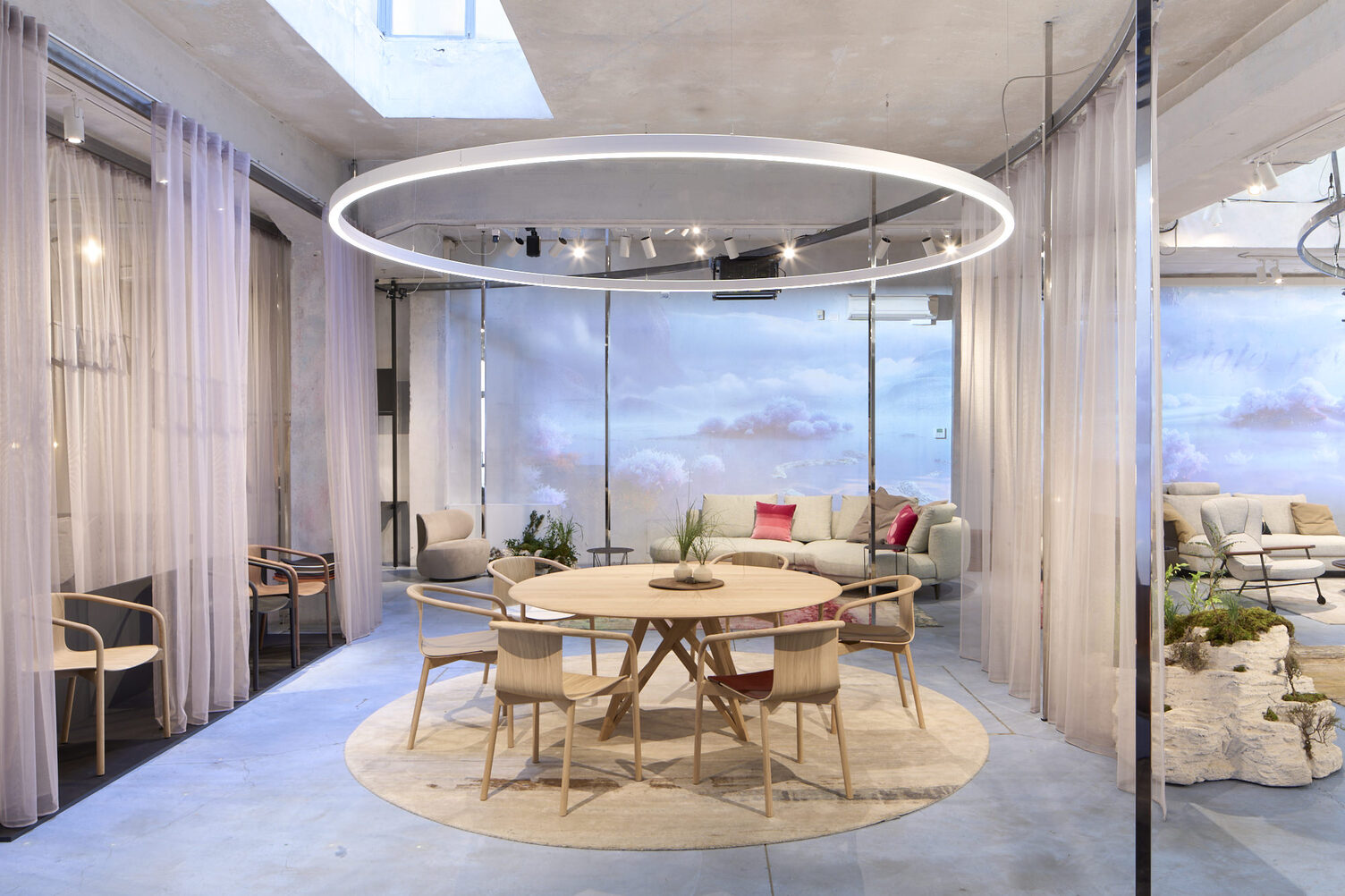 Exhibition stand with cloud walls, curtains and a round ring light (DUETTO) in the centre of attention is a dining table group with chairs from WALTER KNOLL.