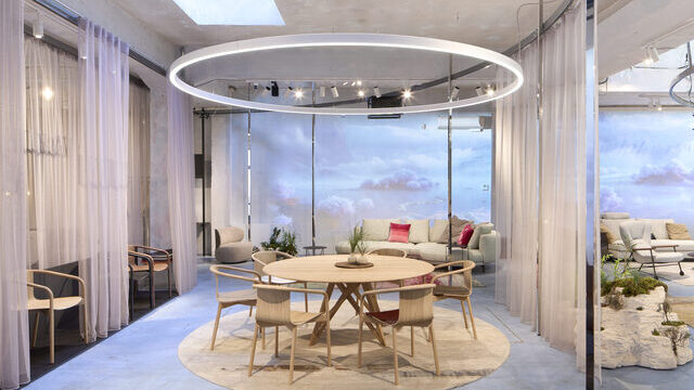 Messestand mit Wolkenwänden, Vorhängen und zentral im Fokus durch eine runde Ringleuchte (DUETTO) in Szene gesetzt ist eine Esstischgruppe mit Stühlen von WALTER KNOLL. | © Philip Kottlorz