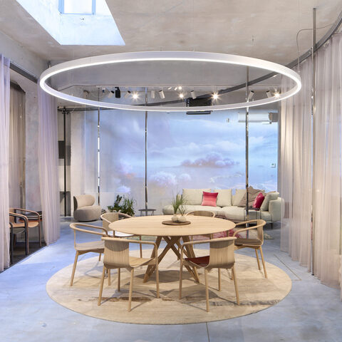 Exhibition stand with cloud walls, curtains and a round ring light (DUETTO) in the centre of attention is a dining table group with chairs from WALTER KNOLL.