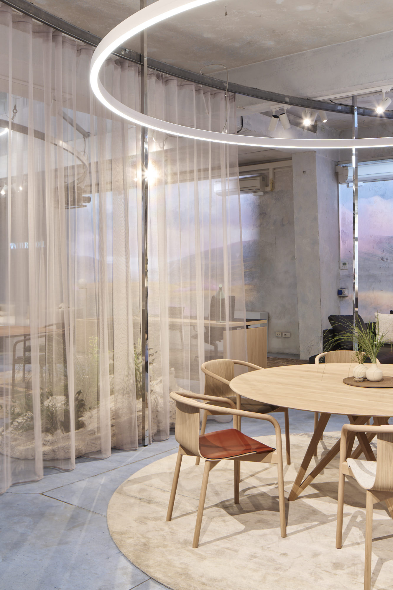 Messestand mit Wolkenwänden, Vorhängen und zentral im Fokus durch eine runde Ringleuchte (DUETTO) in Szene gesetzt ist eine Esstischgruppe mit Stühlen von WALTER KNOLL.