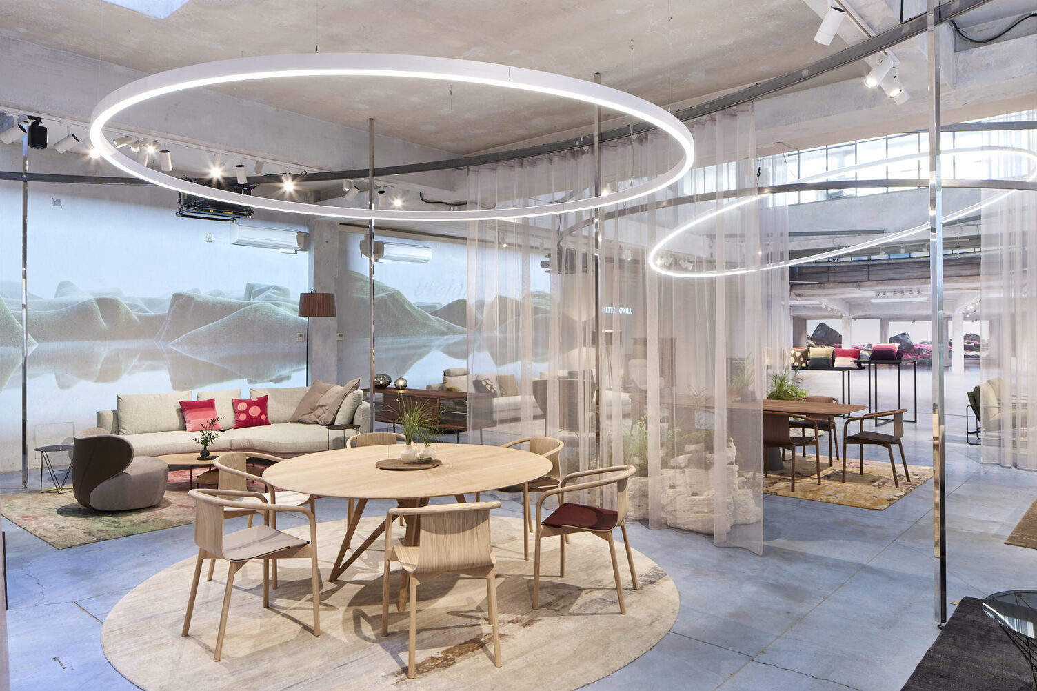Messestand mit Wolkenwänden, Vorhängen und zentral im Fokus durch eine runde Ringleuchte (DUETTO) in Szene gesetzt ist eine Esstischgruppe mit Stühlen von WALTER KNOLL.