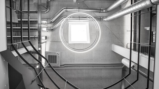 View from below in a stairwell of a concrete industrial building of madness GmbH to the ceiling of 3 INSIEME ring lights suspended one below the other. | © Rönsch Bau GmbH, Kirchheim