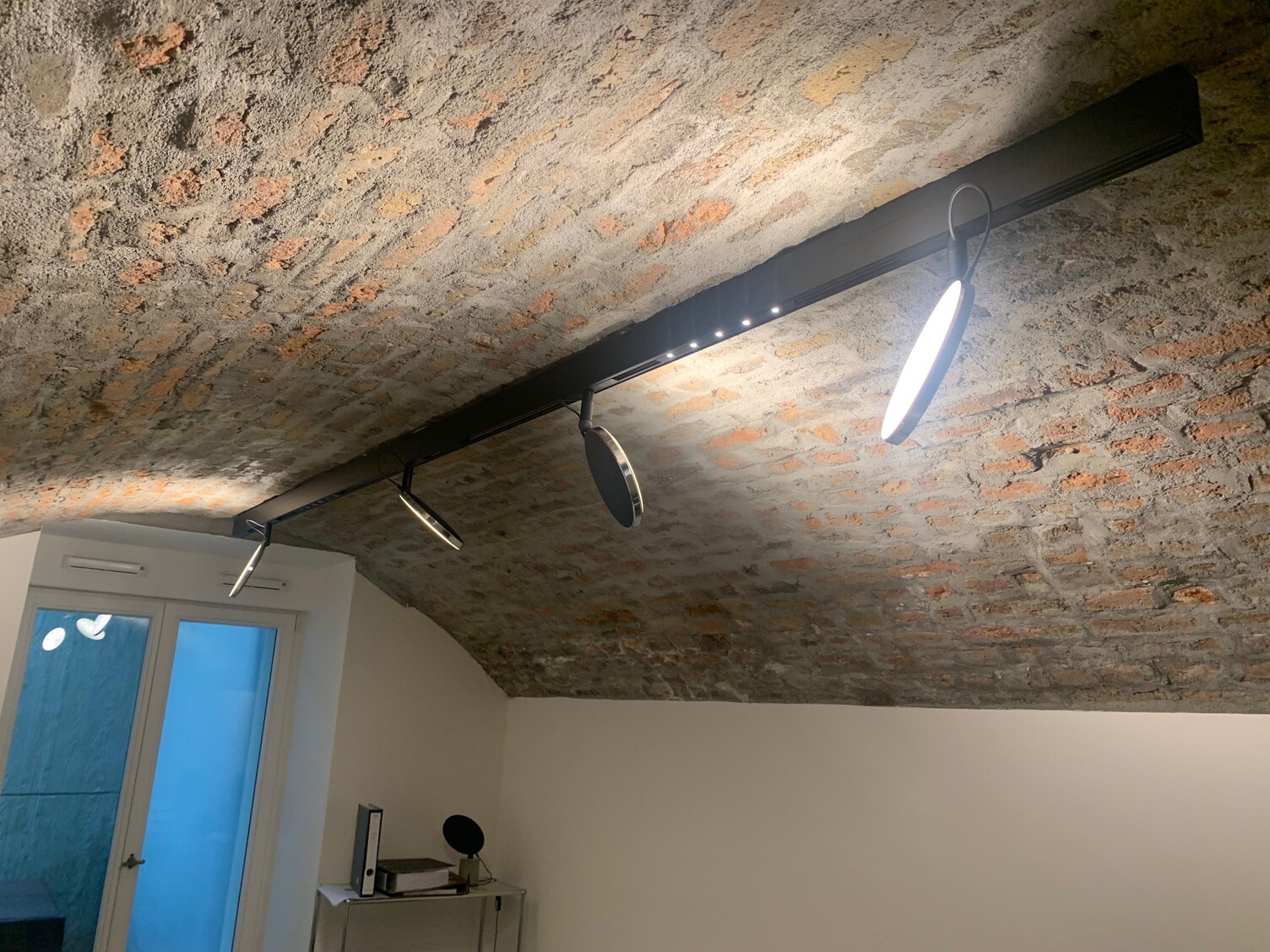 Red brick vaulted ceiling with linear track lighting, PALADIO TRACK, and lighting elements, flat round AVVENI SPOT light heads and linear lighting elements with lens technology.