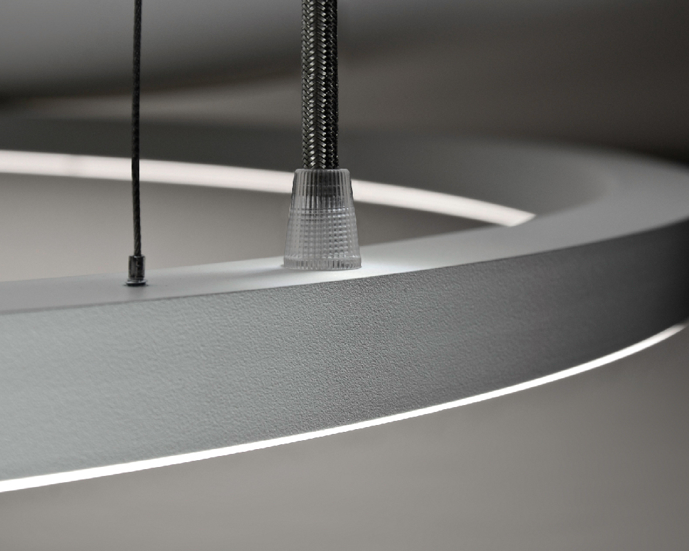 betont sichtbare Lichtkante Ausschnitt einer Ringleuchte, in der der leicht überstehende Diffusor und damit die sichtbare Lichtkante, sowie die Abhängung im Fokus ist.