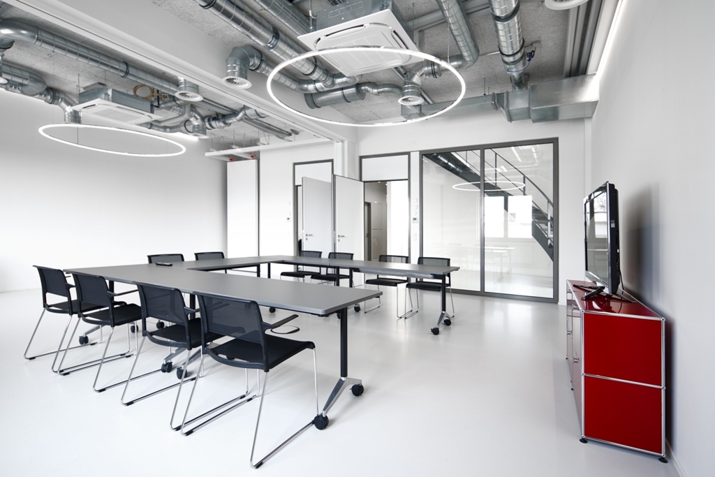 Two SLIM DIRECT LED Ring Lights above U-Shaped Meeting Table Two filigree SLIM DIRECT LED ring pendants by SATTLER suspended above a U-shaped meeting table, providing direct and uniform conference lighting.