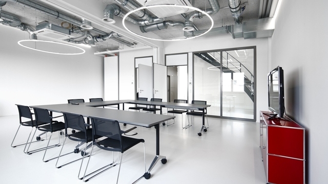 Two filigree SLIM DIRECT LED ring pendants by SATTLER suspended above a U-shaped meeting table, providing direct and uniform conference lighting. | © Tobias Fröhner