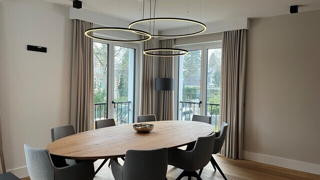 Three filigree SLIM DIRECT LED ring pendants by SATTLER suspended above a dining table in a country-style interior, providing direct and even table illumination.
