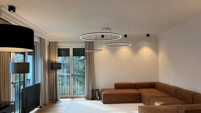 Three filigree SLIM DIRECT LED ring luminaires by SATTLER in a private living room, providing direct and harmonious architectural lighting.