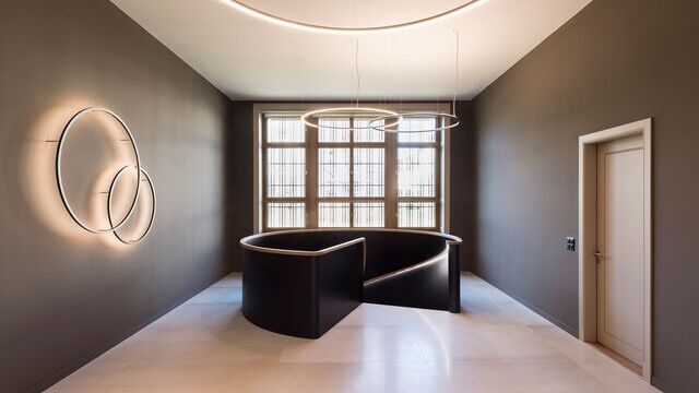 In a historic bank building, Slim Wall luminaires in various diameters were used to create accent lighting and the ceiling height was extended using indirect SLIM luminaires. The SLIM provides direct lighting to illuminate the basic lighting in the corridor area. | © Andreas Zimmermann Fotografie