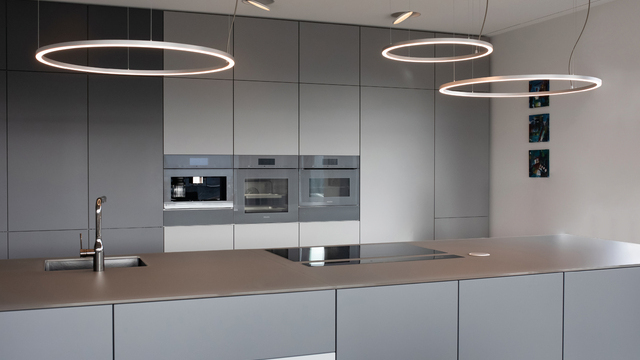 Modern light grey open kitchen 3 small SLIM DIRECT ring lights hang side by side above the kitchen unit, offset in height.