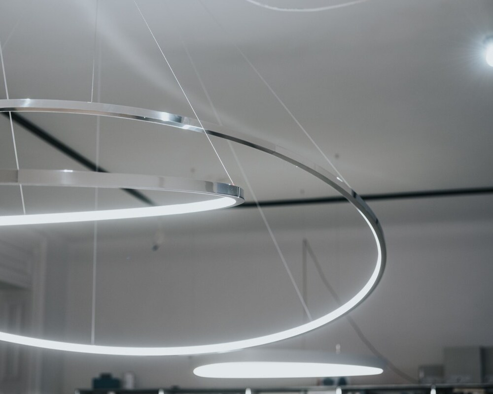 © Gosztom Gergo Detailbild zweier sich überschneidender filigraner Aluminiumringleuchten - Slim In - von SATTLER, die nach innen abstrahlen. | © Gosztom Gergo