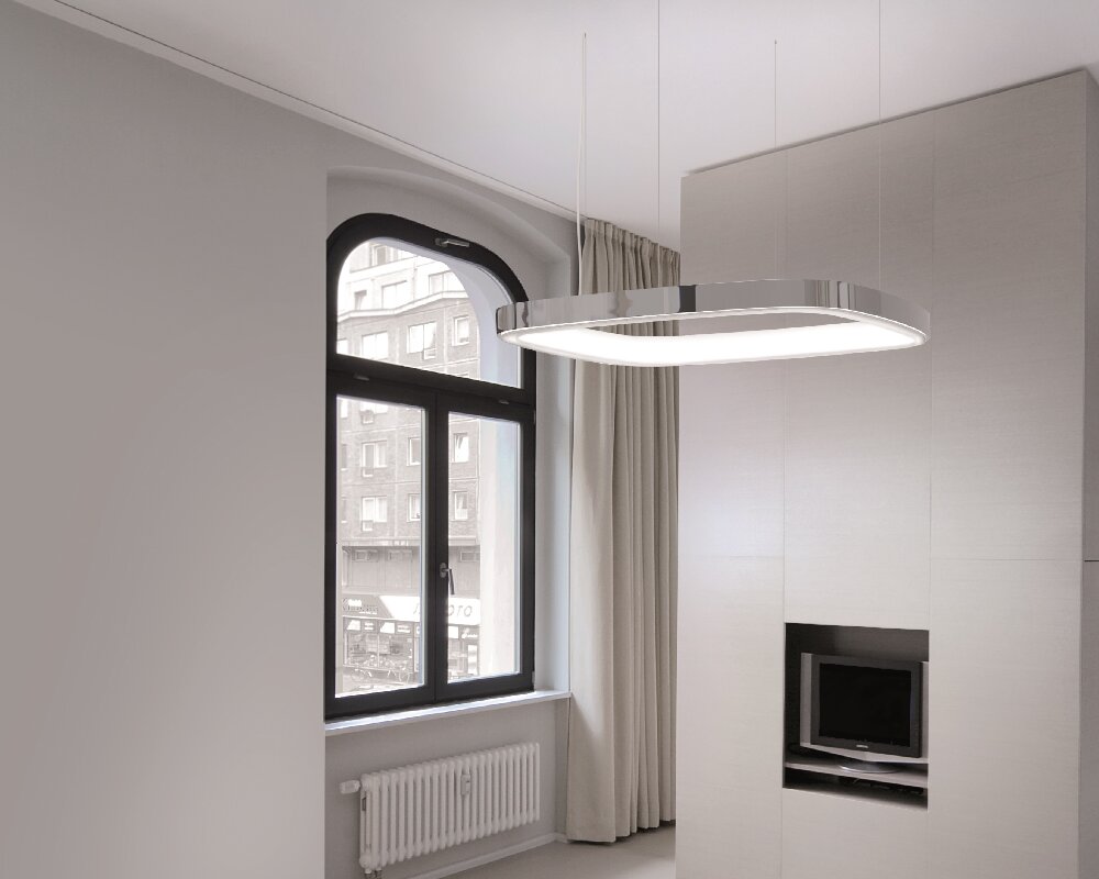 Ring-Pendelleuchte in Form eines abgerundetes Quadrats mit nach unten überstehenden L-Diffusor Große Aluminium-Pendelleuchte in Form eines abgerundeten Quadrats mit L-Diffusor auf der Ringinnenseite, die vor einem Fenster in einem Hotelzimmer abgehangen ist.