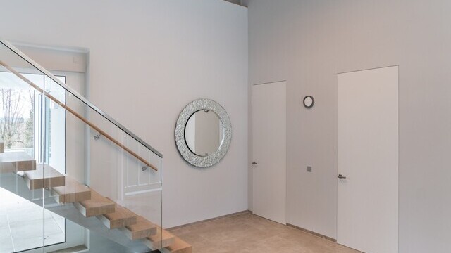 Entrance area with staircase with straight single-flight staircase of a modern private house and focus on decorative lighting thanks to a modern chandelier consisting of 3 TOCCATA ring luminaires.  | © Luminarium
