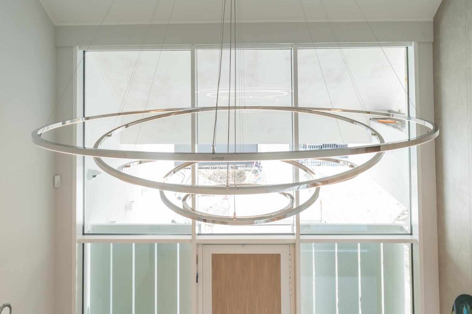 Side view of the TOCCATA, a modern chandelier consisting of several connected individual ring lights that form an inverted pyramid shape.