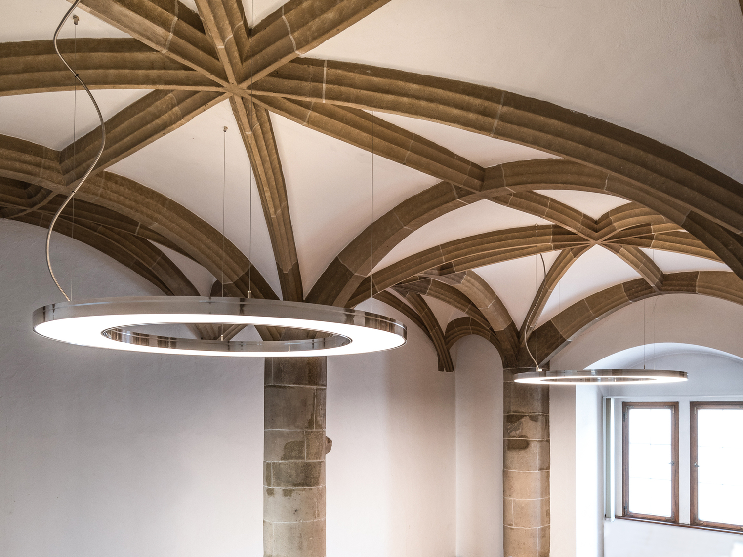 Elegantes Aluminium poliert der Ringleuchten ANELLO passend in historischer Gewölbedecke, weiße Decke und hell steinerne Bögen, des Amtsgerichts Göppingen. | © SATTLER