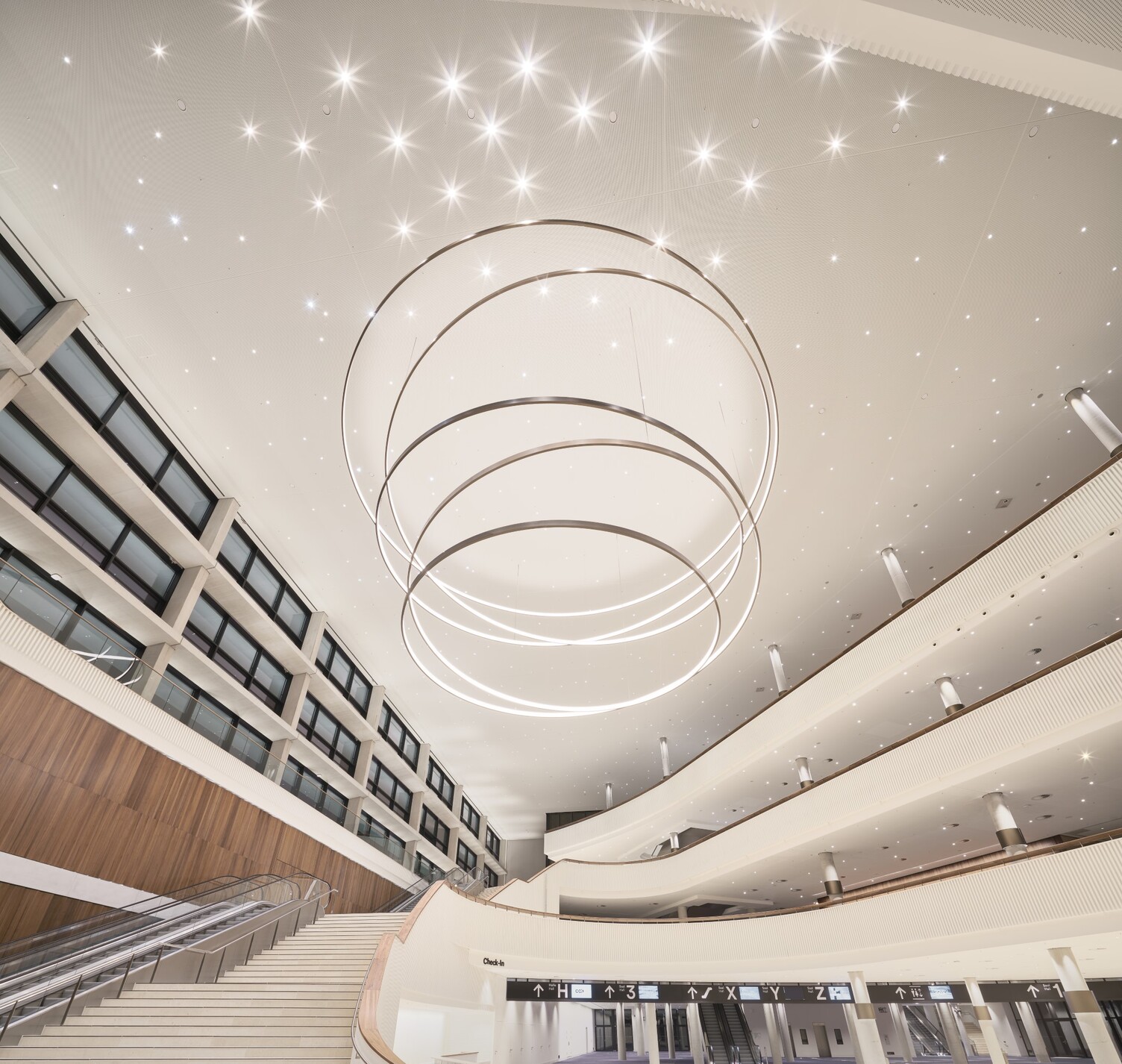 Atrium des Congress Center Hamburg mit großen LED-Ringleuchten von Sattler - Leuchte in einem steilen Winkel aus fotografiert.