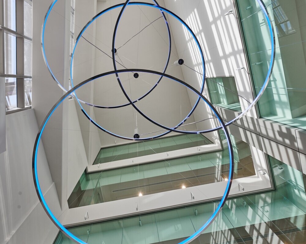 LED technology: white, tunable & RGB (also in combination) | © © LUMIERE GROUP View from the below in a glass atrium up to 4 x CIRCOLO-I ring luminaires with pendant canopy, Ø 3500mm, polished aluminium housing and light blue glow, 12 x AVVENI single spots on the walls. | © © LUMIERE GROUP