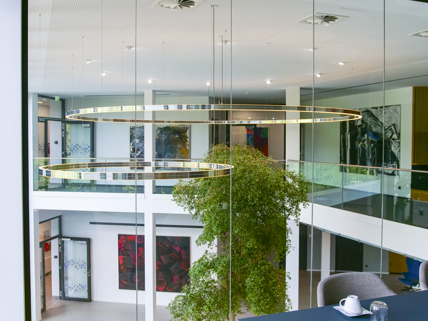 DOPPIO Sonderleuchte als zentrales Gestaltungselement Zweigeschossiger Empfang mit Baum und DOPPIO Sonderleuchte bei DAHLHAUSEN Medizintechnik.