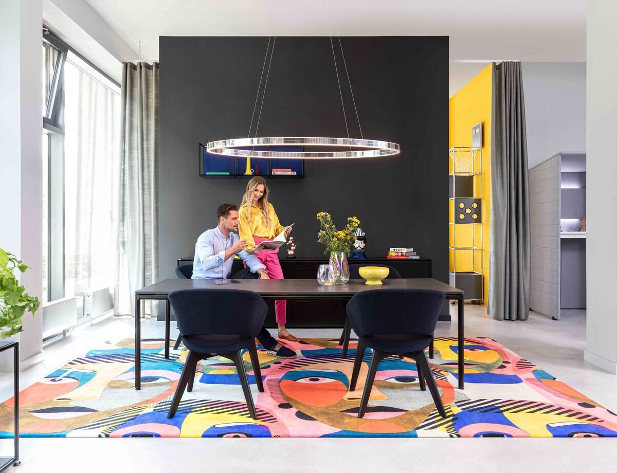 Moderner Showroom mit farbenfrohem Teppich und stilvoller Beleuchtung in Offenbach, mit Sattlers Doppio Ellipse Beleuchtung.