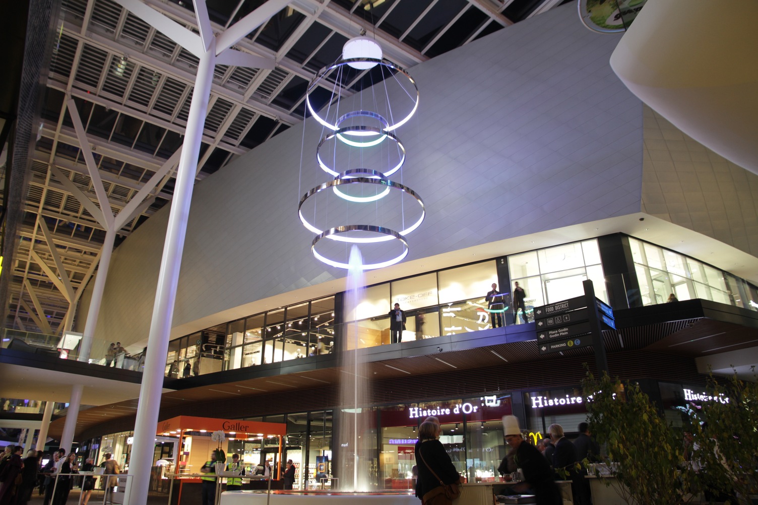 Water fountain in shopping mall, above it a project luminair, a light object consisting of several ring lights (CIRCOLO) on top of each other.