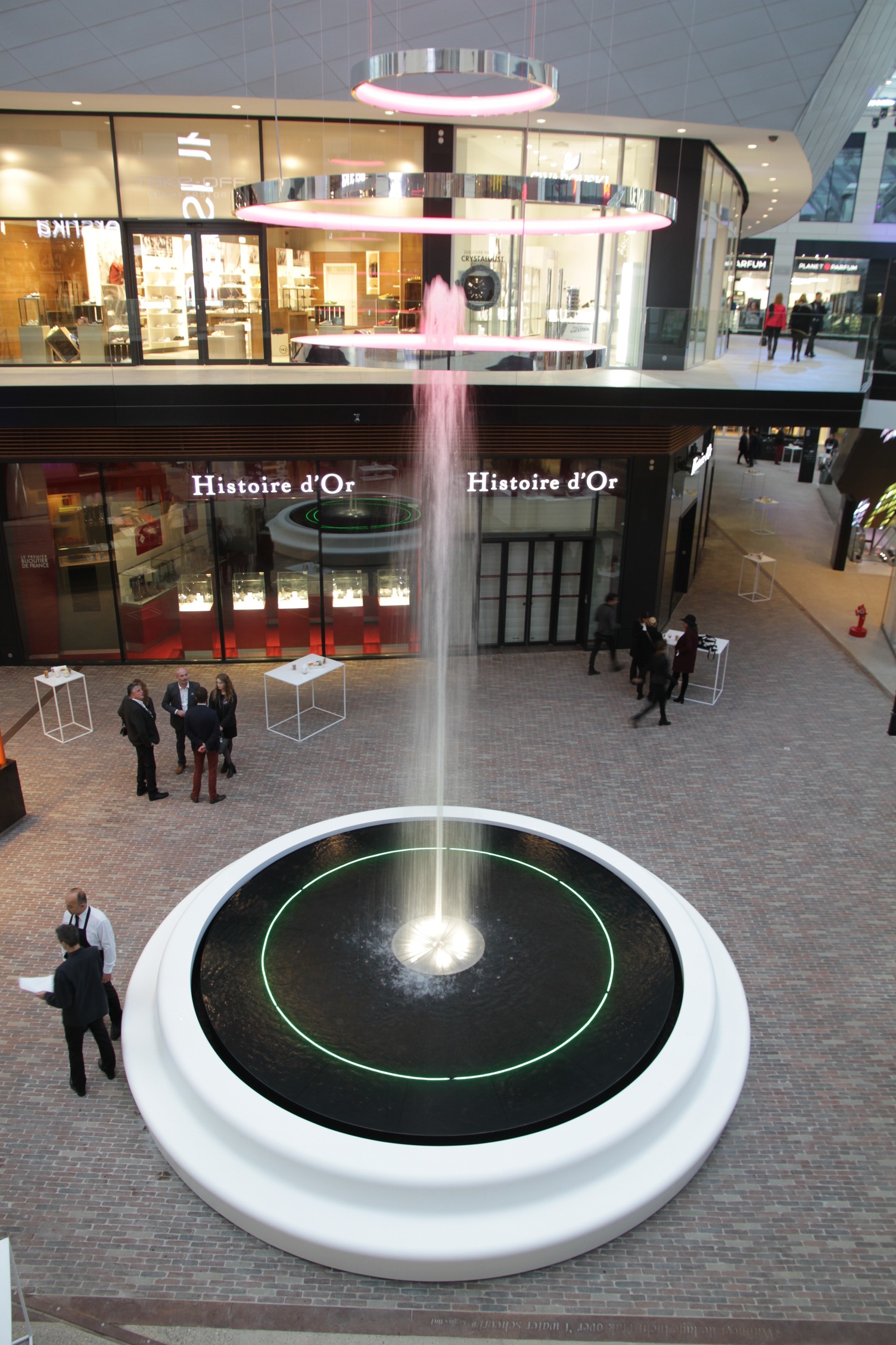 Water fountain in shopping mall, above it a project luminair, a light object consisting of several ring lights (CIRCOLO) on top of each other.