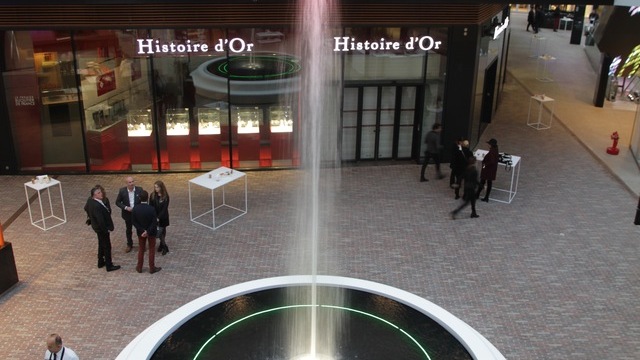 Wasserspringbrunnen in Shopping Mall, darüber eine Sonderleuchte, ein Lichtobjekt aus mehreren Ringleuchten (CIRCOLO) übereinander. 