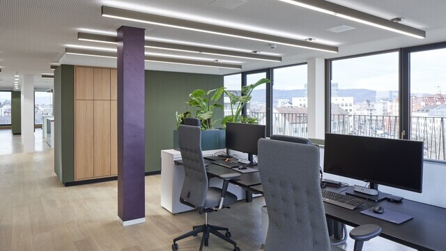 Open Office der Evangelischen Bank Kassel mit linearen PALADIO Leuchten und Arbeitsplätzen am Fenster