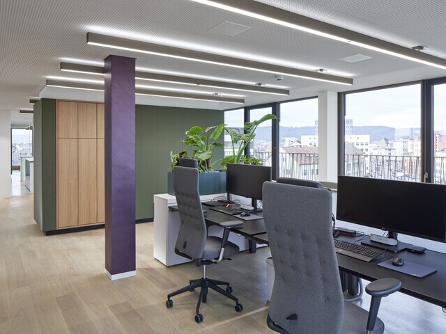 Open Office der Evangelischen Bank Kassel mit linearen PALADIO Leuchten und Arbeitsplätzen am Fenster