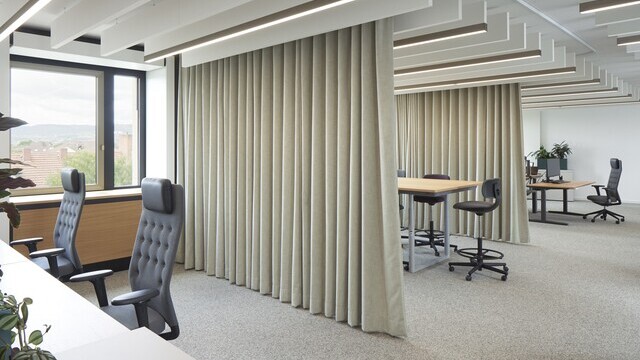 Open-plan office at Evangelische Bank Kassel with linear luminaires and white acoustic baffles