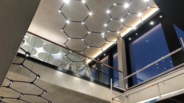 SATTLER FAVO THE LIGHT NET – Lichtinstallation an der Decke über der schwarzen Wendeltreppe