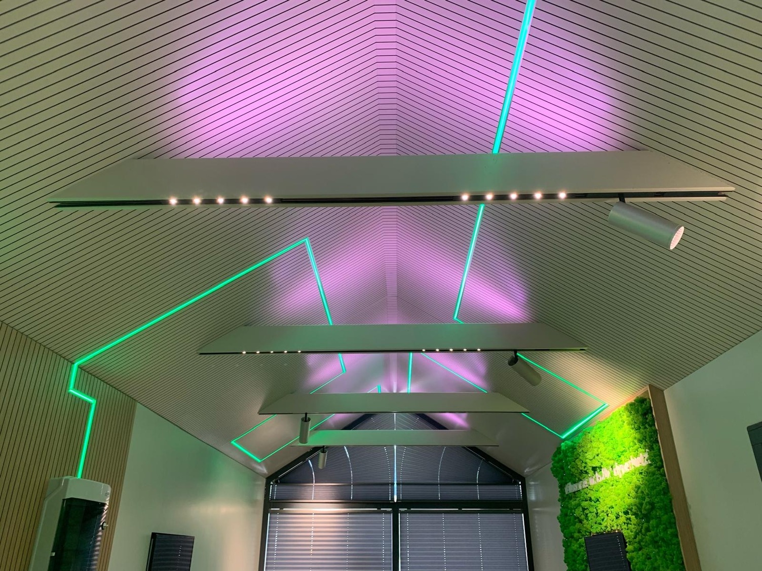 Deckenbeleuchtung mit modernen LED-Leuchten in einem Tiny House, kombiniert mit indirekter Lichtführung in Grün und Violett.