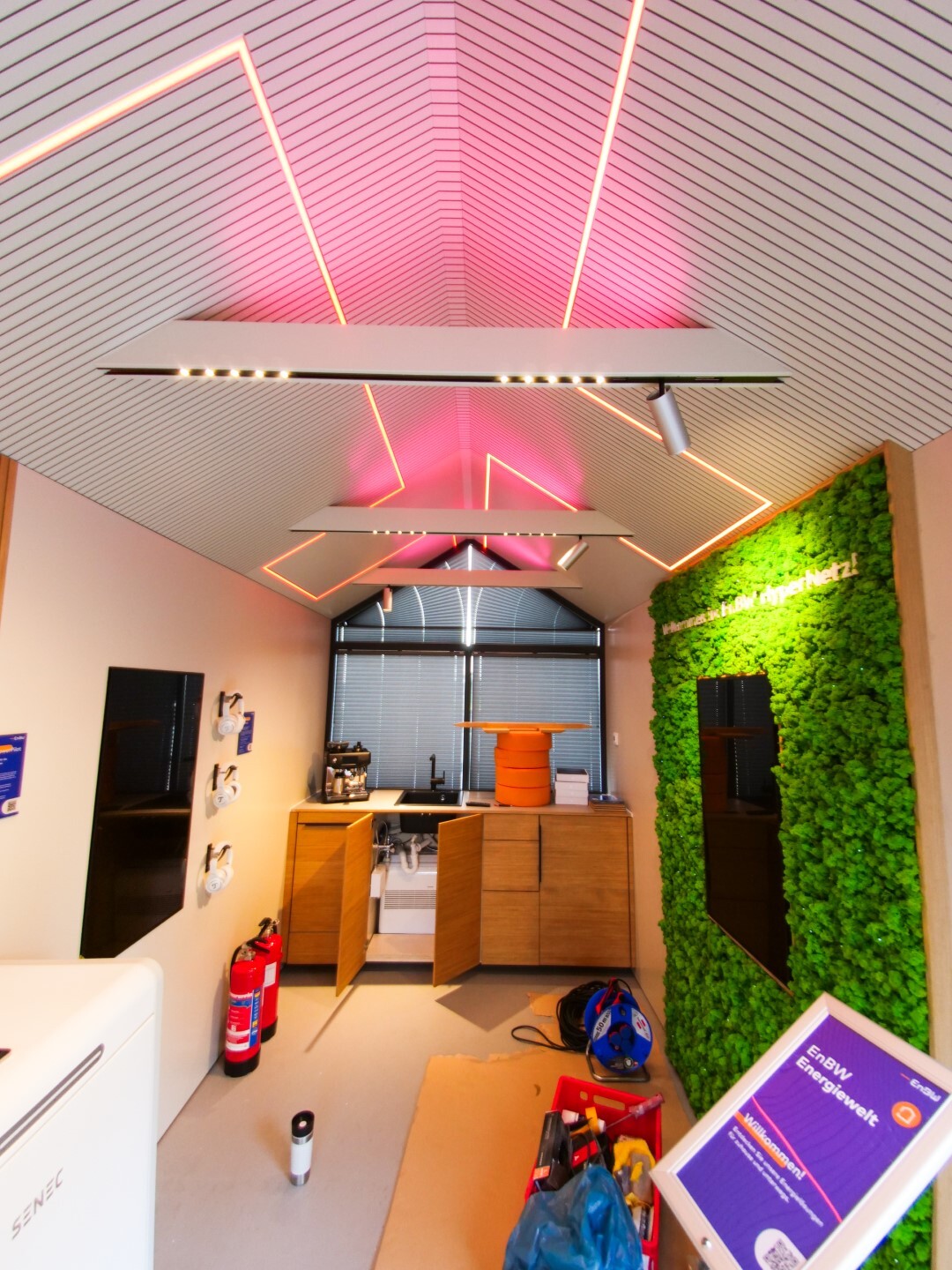Innenansicht eines Tiny Houses mit LED-Deckenbeleuchtung und Holzmöbeln.
