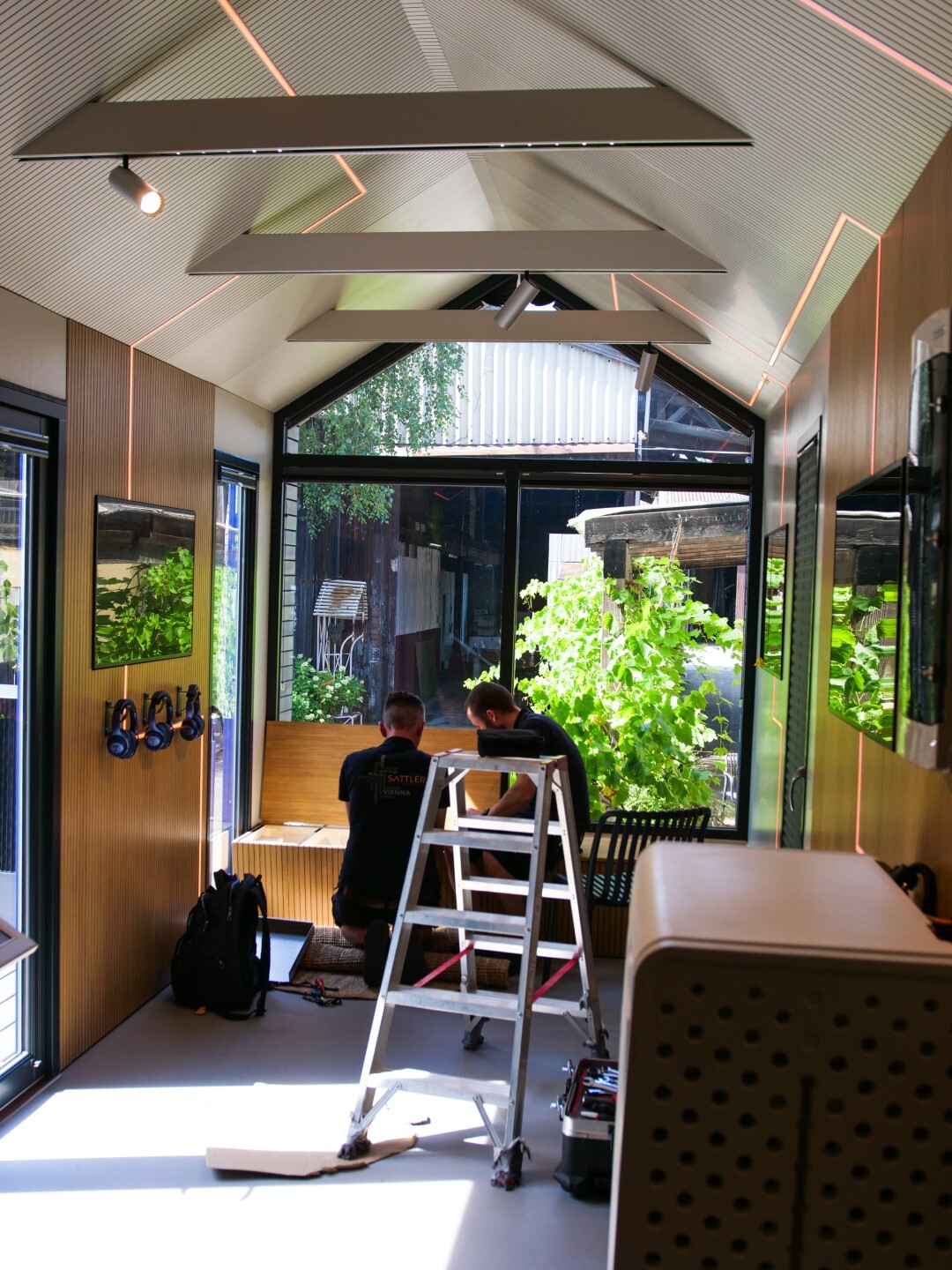 Zwei Handwerker arbeiten am Innenausbau eines Tiny Houses mit moderner Beleuchtung.
