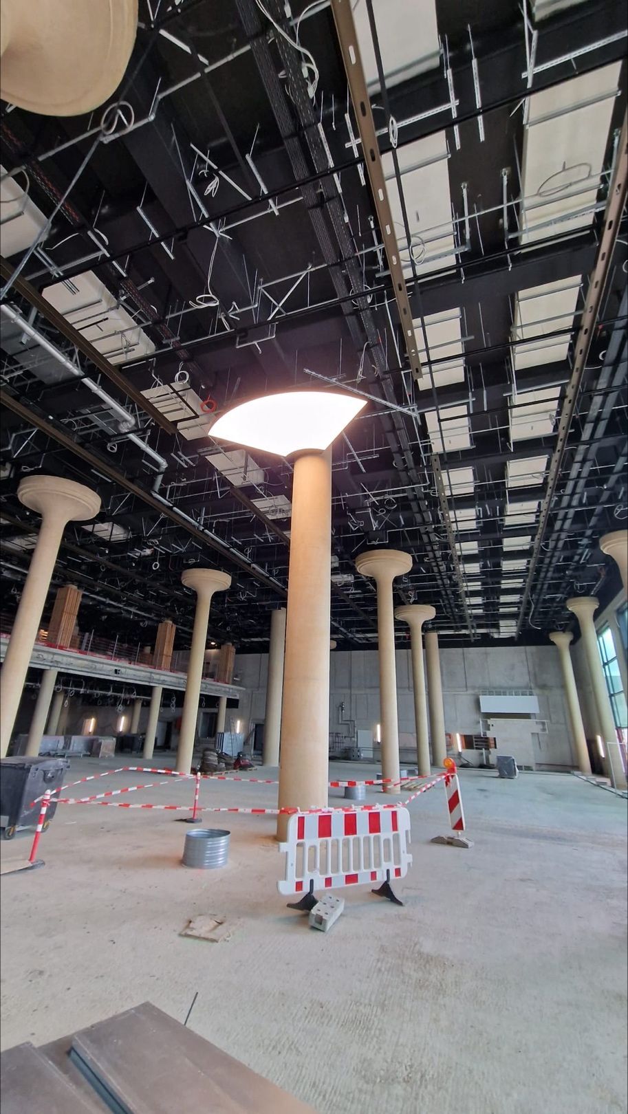 Große Halle mit mehreren Säulen. Um eine Säule ist ein Viertelkreis-Lichtdecken-Segment Deckennah montiert und leuchtet. | © SATTLER