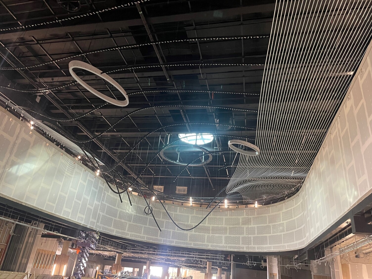 Marktplatz Terminal 3 Fraport - Metalldecke im Aufbau mit wellenförmigen Elementen und Kreisrunden Ausschnitten. Entwurf LAVA, Umsetzung Metalldecke: ARNOLD. | © SATTLER