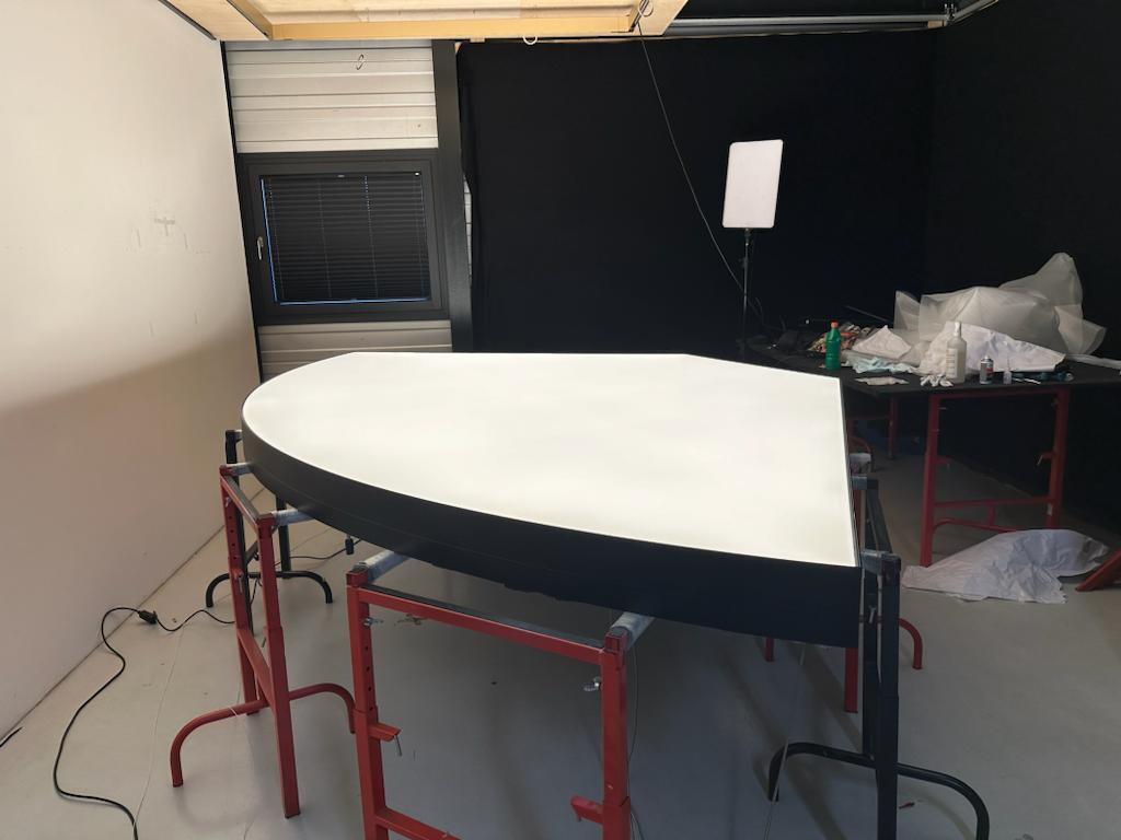 1/4 Kreissegment Lichtdecke mit schwarzem Rahmen im Testraum in der SATTLER Produktion. Aufgebahrt auf Böcken mit Leuchtfläche nach oben. | © SATTLER