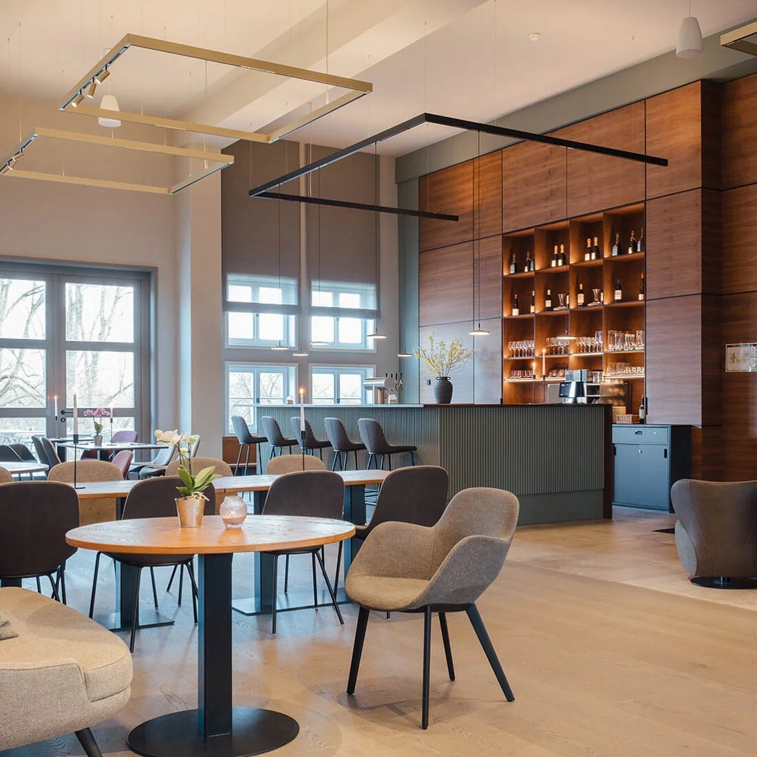Hotel restaurant and bar at the Nattika Ayurveda Hotel in Berlin Alt Rhese ‘Park am See’. Lighting provided by PALADIO series luminaires suspended in a square formation with EVOLUTION SPOTS, and in an open horseshoe shape above the bar with AVVENI PENDANT 1 pendant luminaires. | © https://www.cremeguides.com/berlin/retreat-park-am-see-nattika-ayurveda/