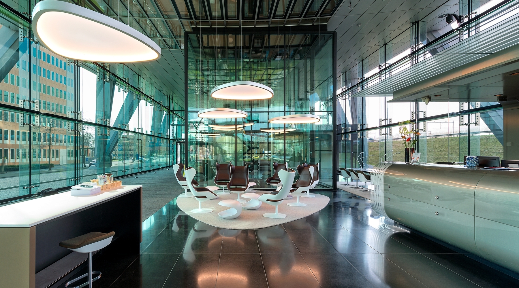Soft Delta L+A over seating areas of a lobby | © SATTLER | Nathalie Peters Fabric-covered Soft Delta Light & Acoustic luminaires from SATTLER in a modern glass lobby with reception and cafeteria | © SATTLER | Nathalie Peters