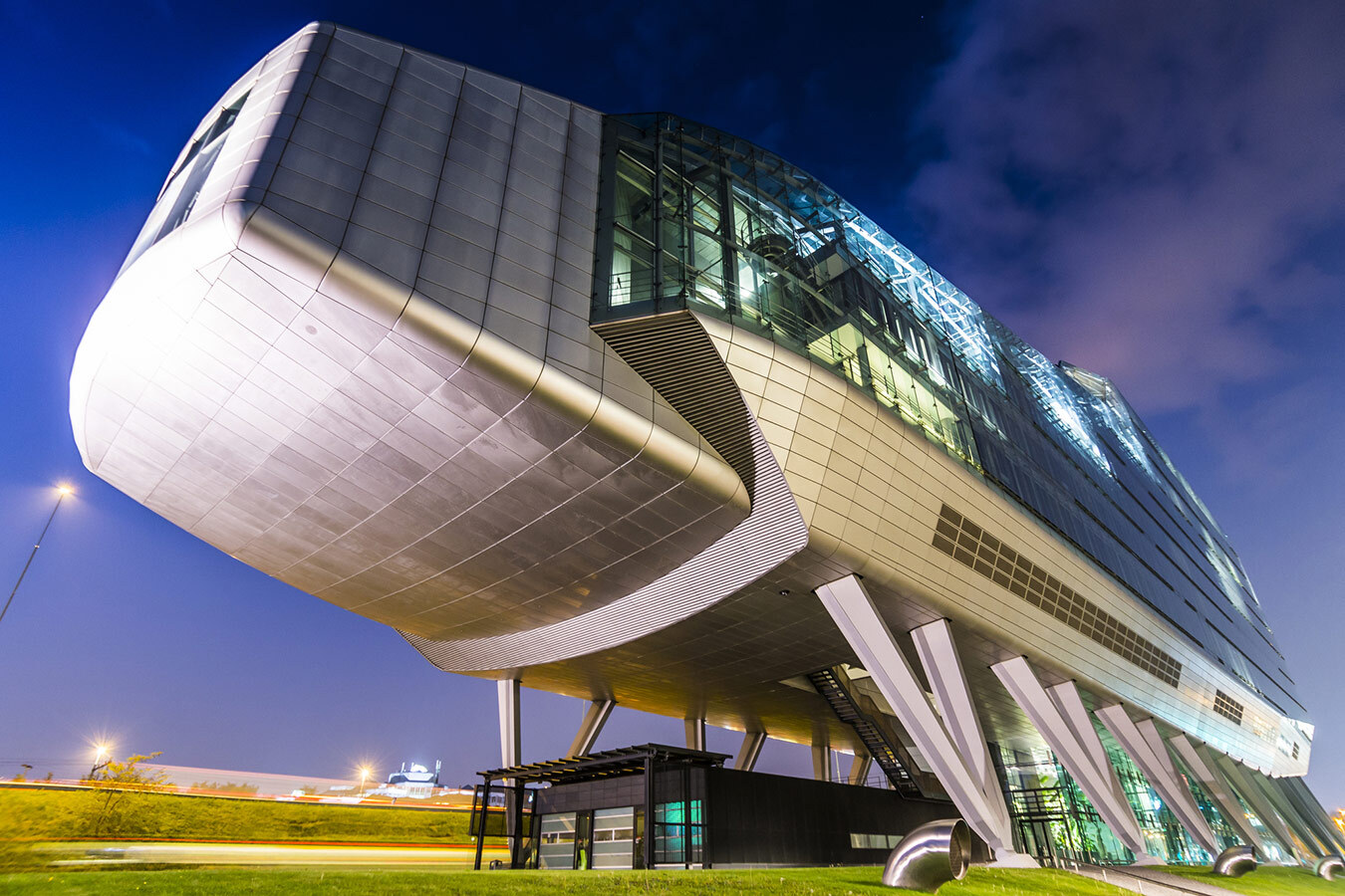 Night-time exterior view of the futuristic Infinity building on stilts in Amsterdam. Double-walled glass and metal office building constructed on stilts right next to a motorway in the Netherlands.