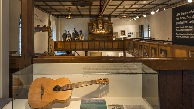 A museum housed in a historic building, with a guitar on display in a showcase in the foreground. Round, flat AVVENI light heads are arranged across the gallery, mounted on a track. | © Rose Hajdu, Stuttgart